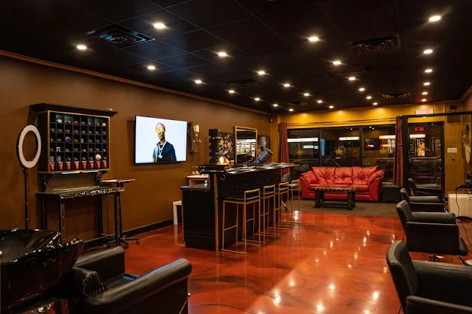 Le salon Suavé : fauteuils noirs, murs dorés et canapé en cuir rouge.